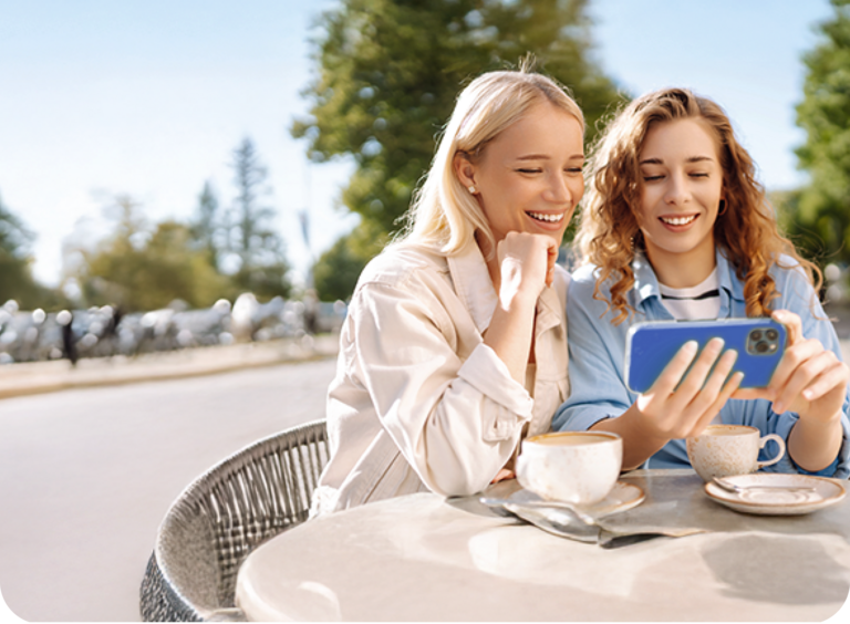 Zwei junge Frauen sitzen im Café und nutzen die günstigen Handytarife ohne Handy von BIGSIM.