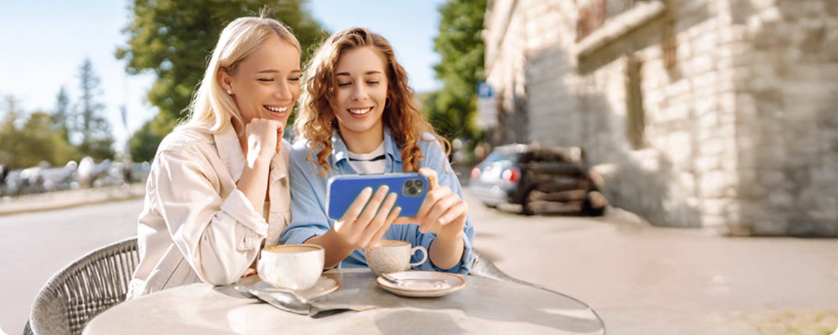 Zwei junge Frauen sitzen im Café und nutzen die günstigen Handytarife ohne Handy von BIGSIM.